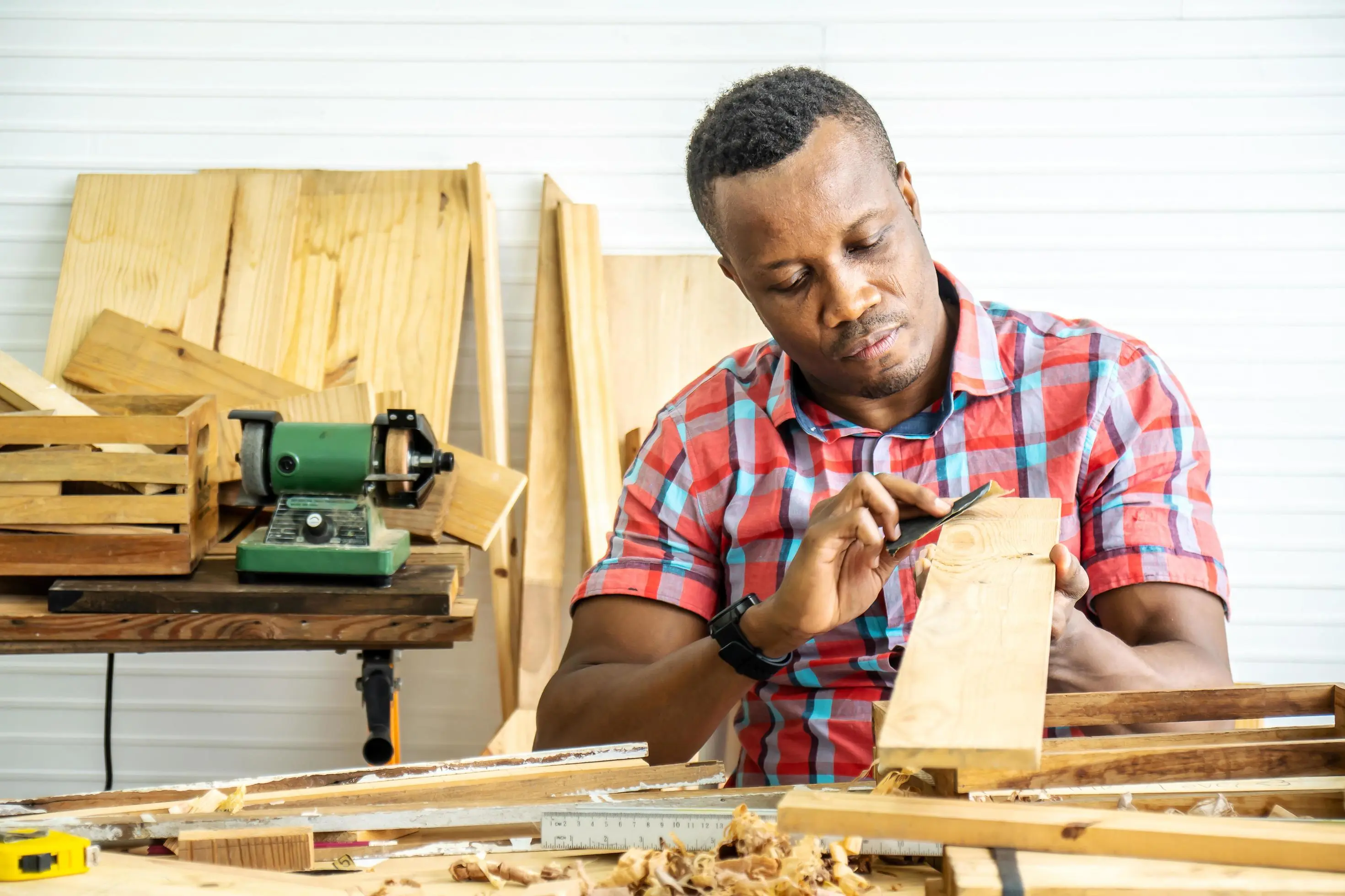young-carpenter-african-american-man-looking-and-choosing-wood-and-using-sandpaper-to-rub-wooden-plank-at-workshop-table-in-carpenter-wood-factory-free-photo